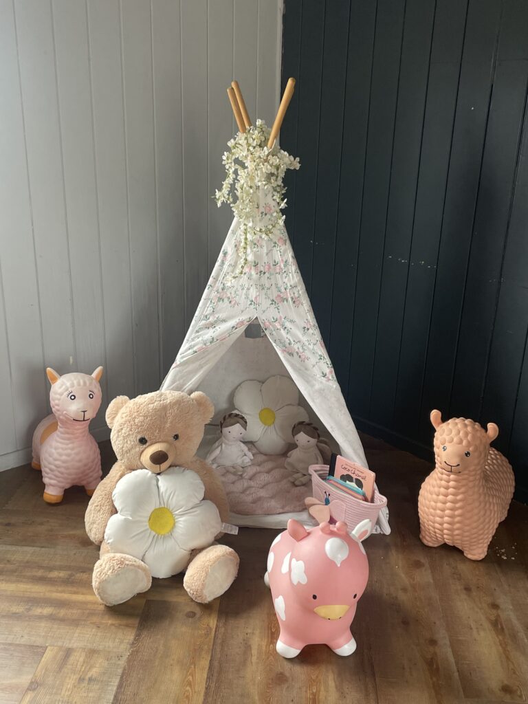 White textured teepee surrounded by soft toys and animal hoppers