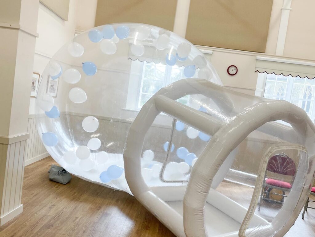 Bubble house igloo with blue and white balloons flying inside